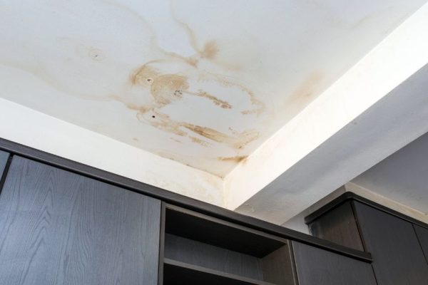 Ceiling with large brown water stains and damage above dark-colored cabinets, indicating a possible leak or moisture problem. | Supremo Exteriors